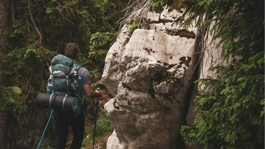 A hiker with a pack on a rocky trail on Velebit